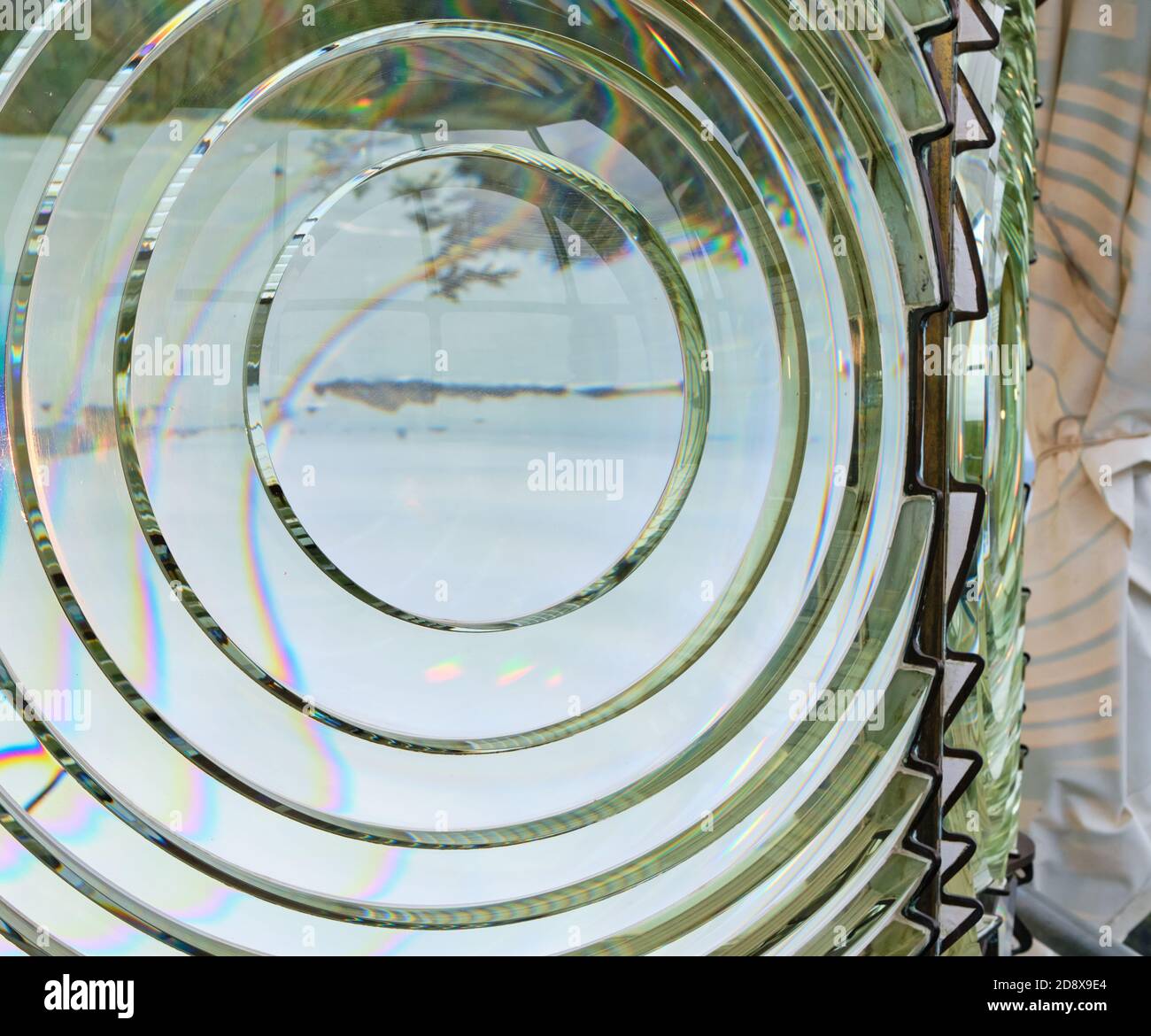 Close-up of Cape Blanco Lighthouse's Fresnel lens showing inverted image of foggy coast...islands and trees... and colorful splashes due to refraction Stock Photo