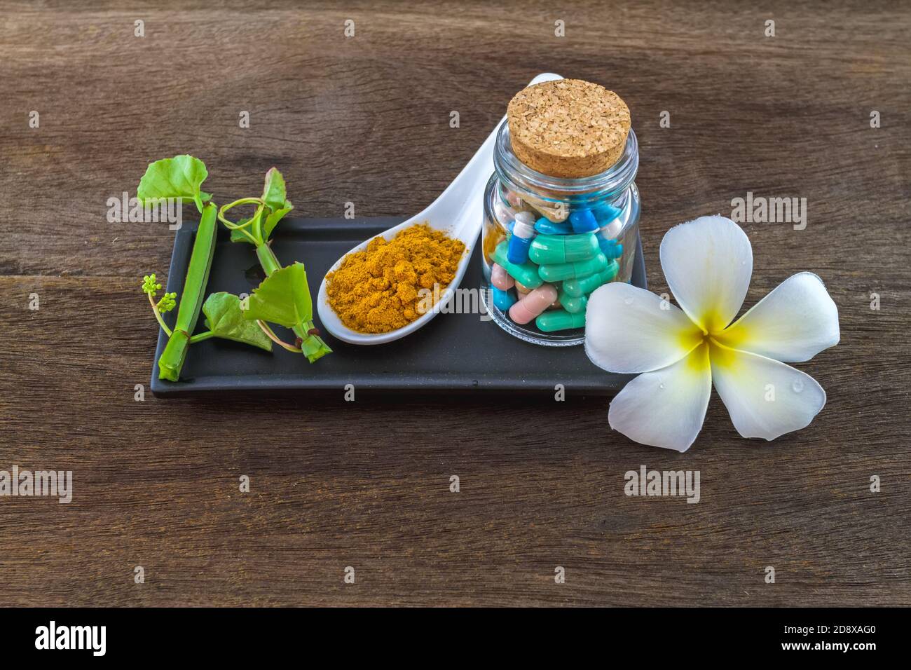 Spa herbal (white frangipani flowers, turmeric powder in white spoon ,pill,Cissus Quadrangularis Linn) on wooden background Stock Photo