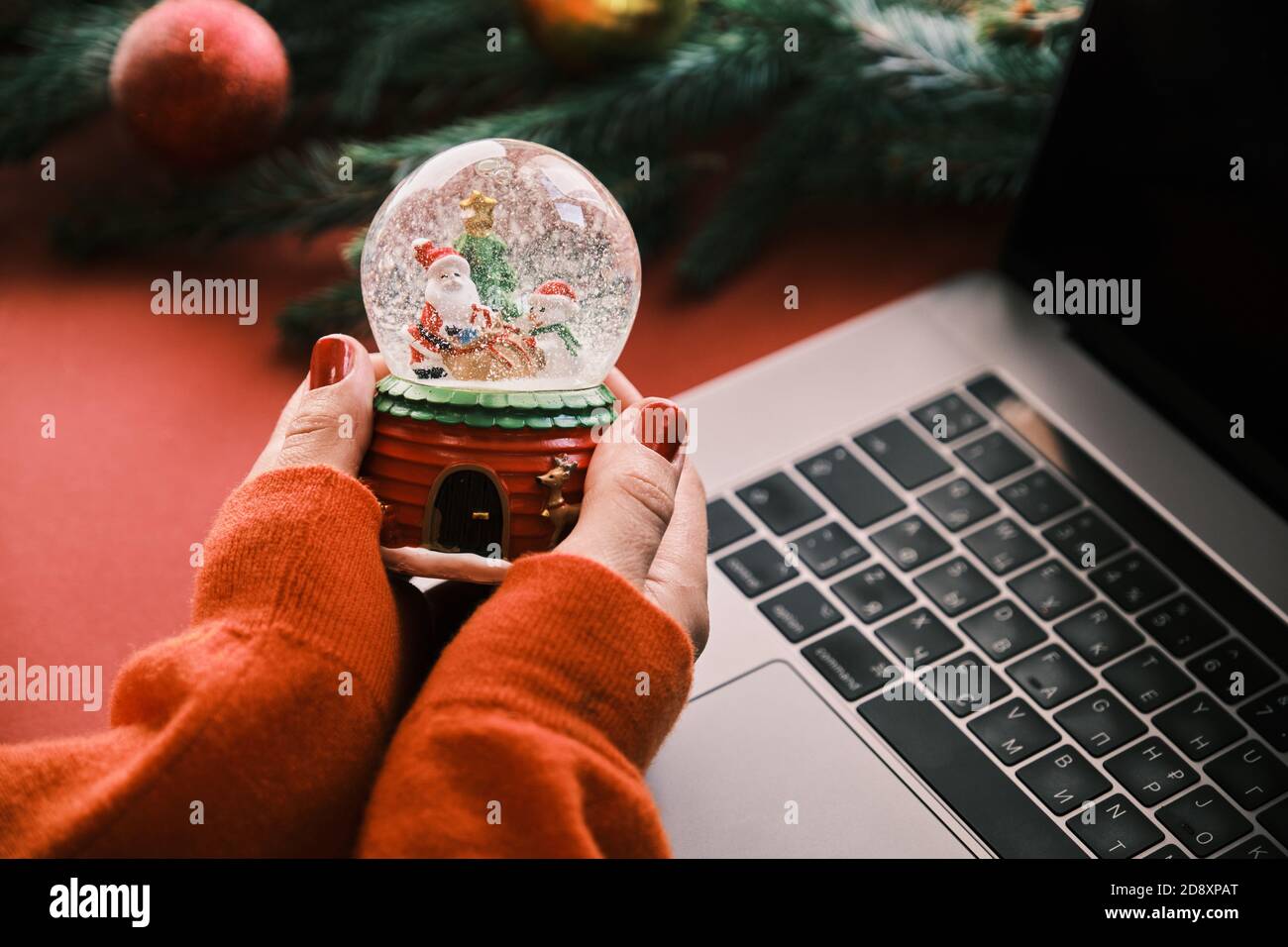 Closeup of Snow Globe Snow Flakes and Santa in hands, Beautiful Holiday Concept with Christmas tree. Working at home Stock Photo