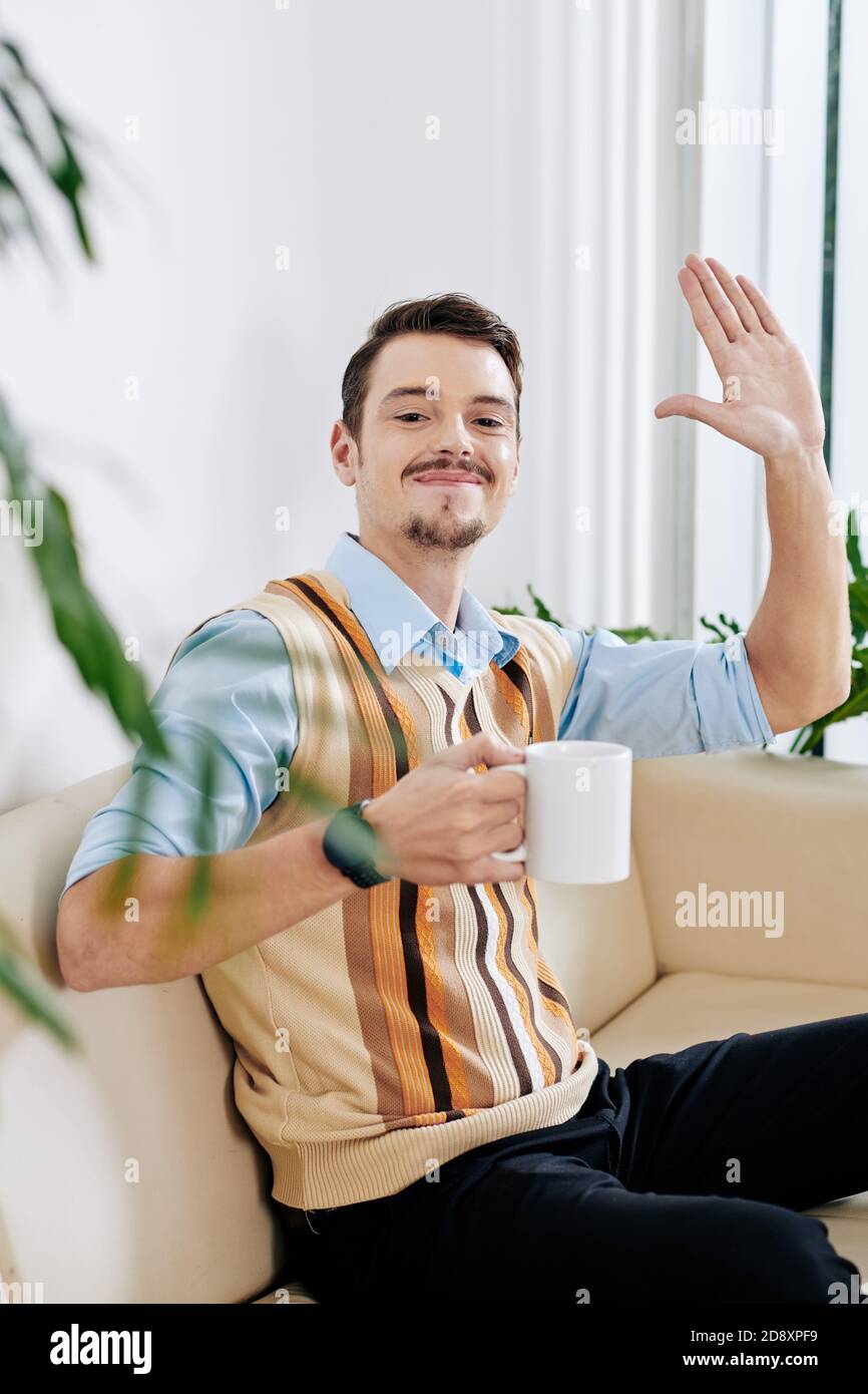 Smiling man waving with hand Stock Photo - Alamy
