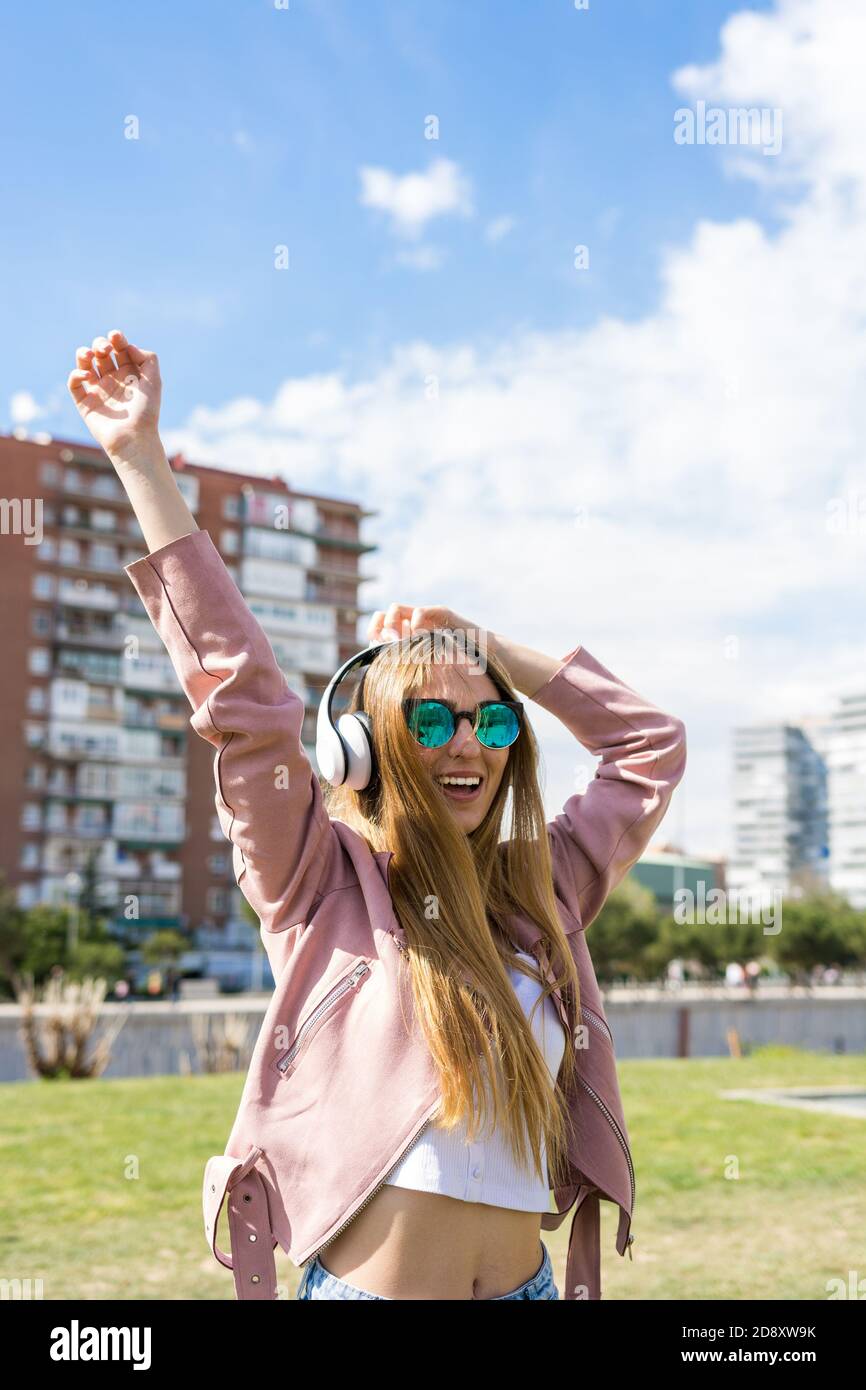 Young and happy girl is dancing while listening to music with her ...