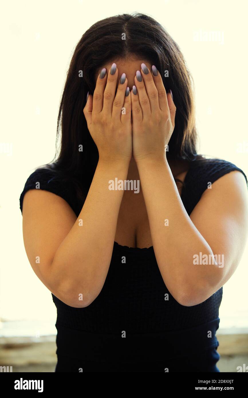Scared woman hiding face with hands crying Stock Photo