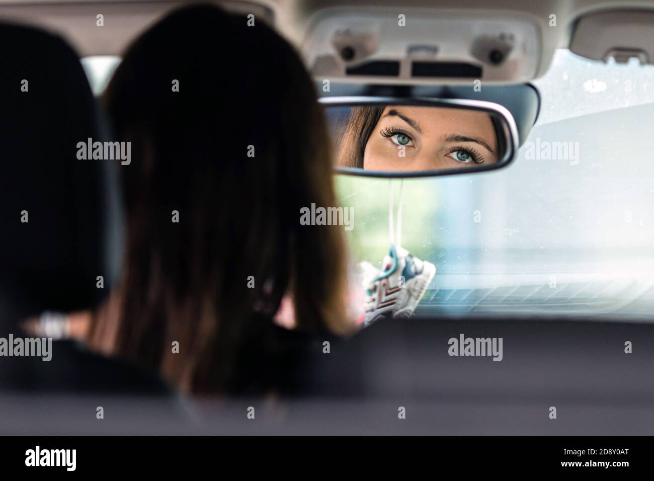 the beautiful eyes of the young driver woman are reflected in the rear ...