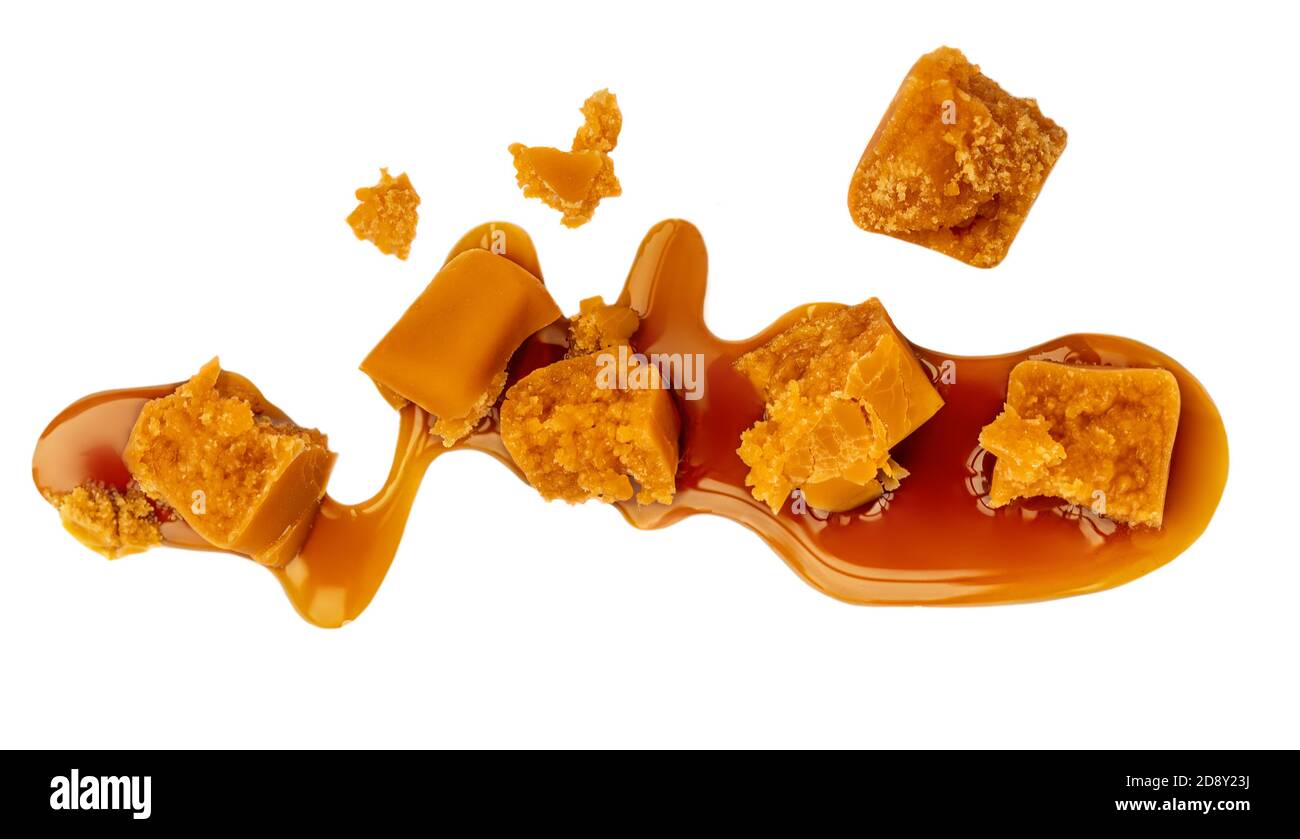 Caramel sauce flowing on caramel candies, isolated on white background
