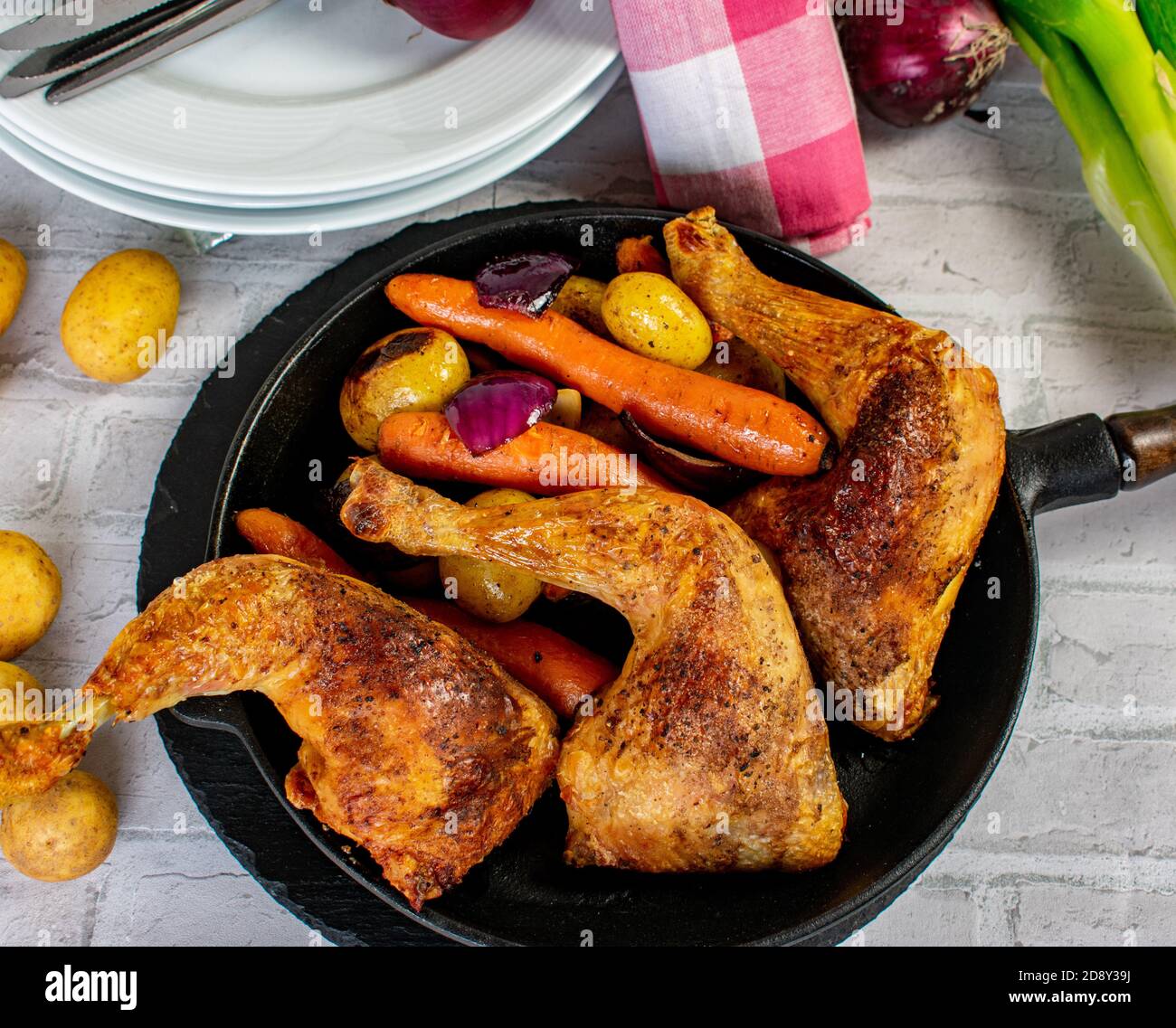 roasted chicken legs with oven baked vegetables served in a rustic iron