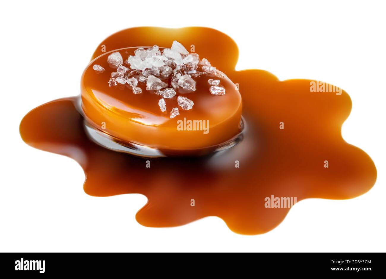 Caramel sauce flowing over salted caramel candies, isolated on white