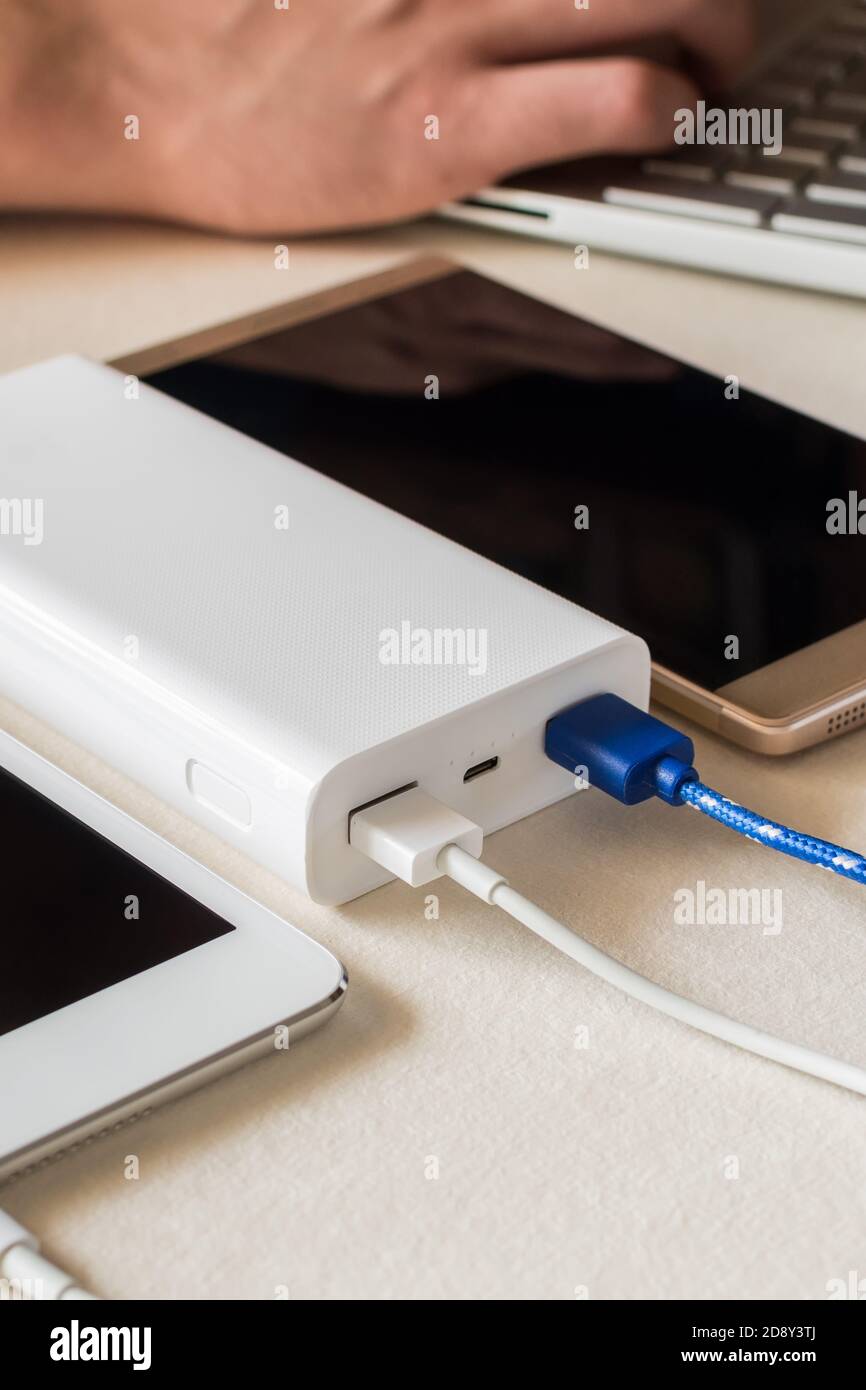 Power bank charges cell phone and tablet on desk Stock Photo Alamy