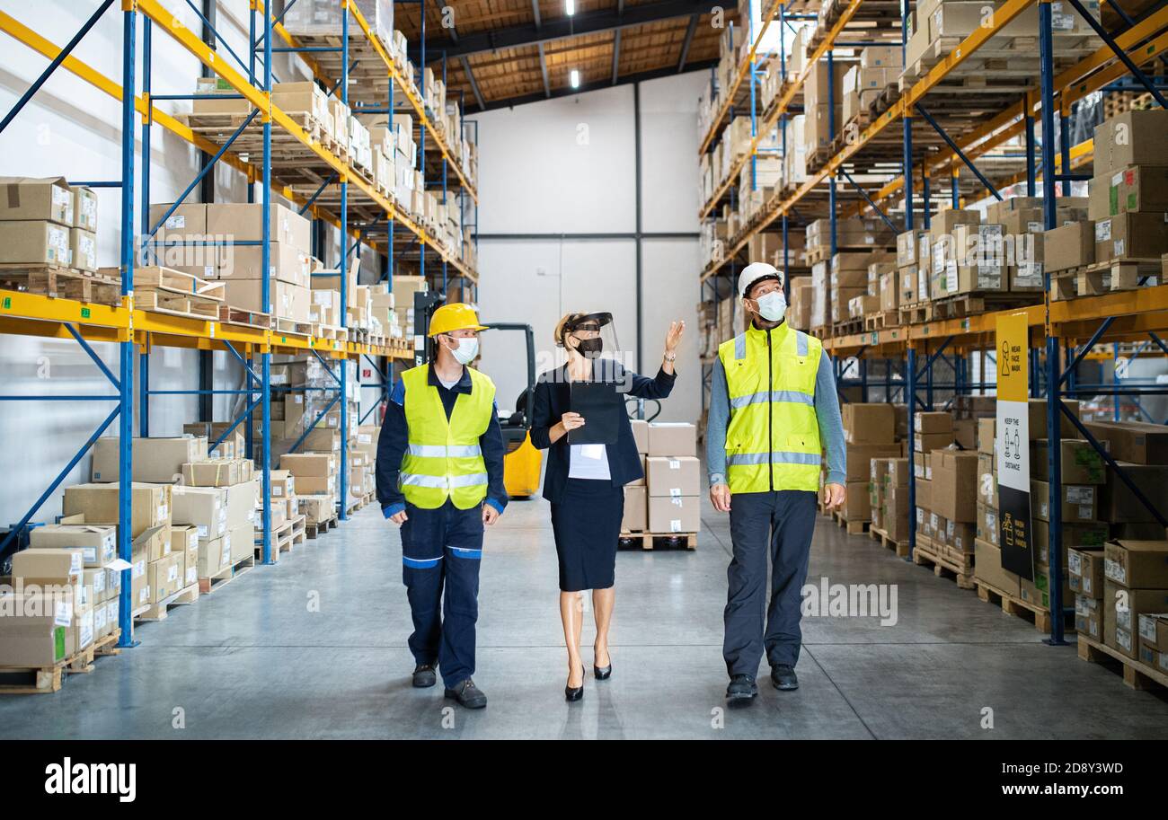 Group of workers with manager working indoors in warehouse, coronavirus concept. Stock Photo