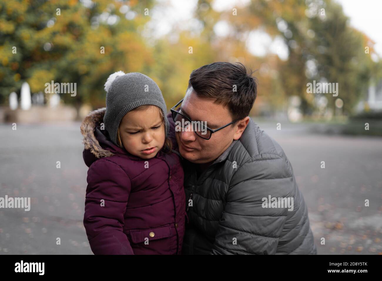 Father comforting toddler child, parent support. Autumn, yellow leaves. Outdoors kids activity Stock Photo