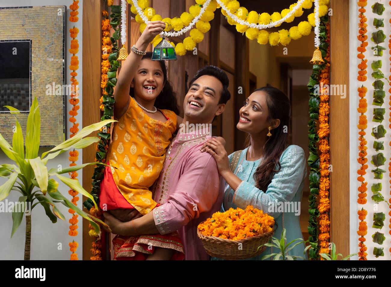 PORTRAIT OF A HAPPY FAMILY LOOKING AT FANCY LANTERN AND POSING IN FRONT OF DECORATED ENTRANCE Stock Photo