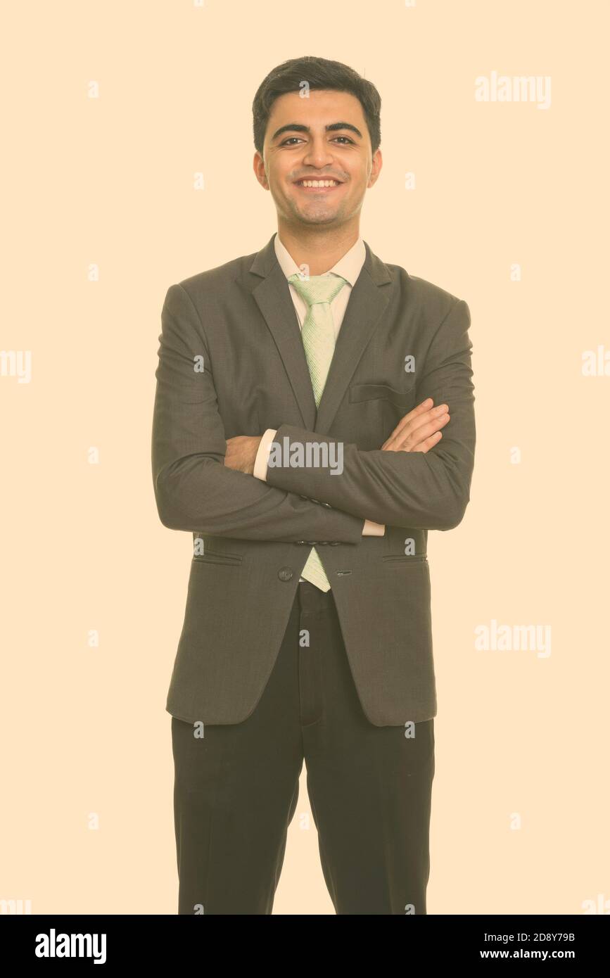 Portrait of happy young handsome Persian businessman in suit smiling ...