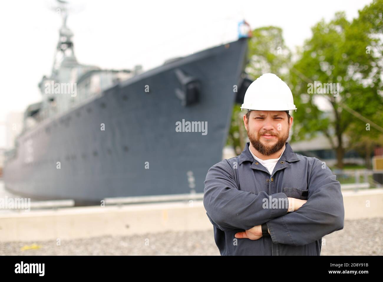 Portrait of marine captain standing near big vessel in background. Stock Photo