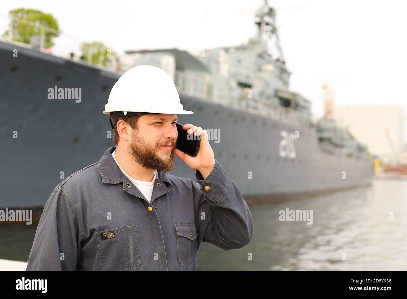Marine captain talking by VHF walkie talkie near vessel in background. Stock Photo