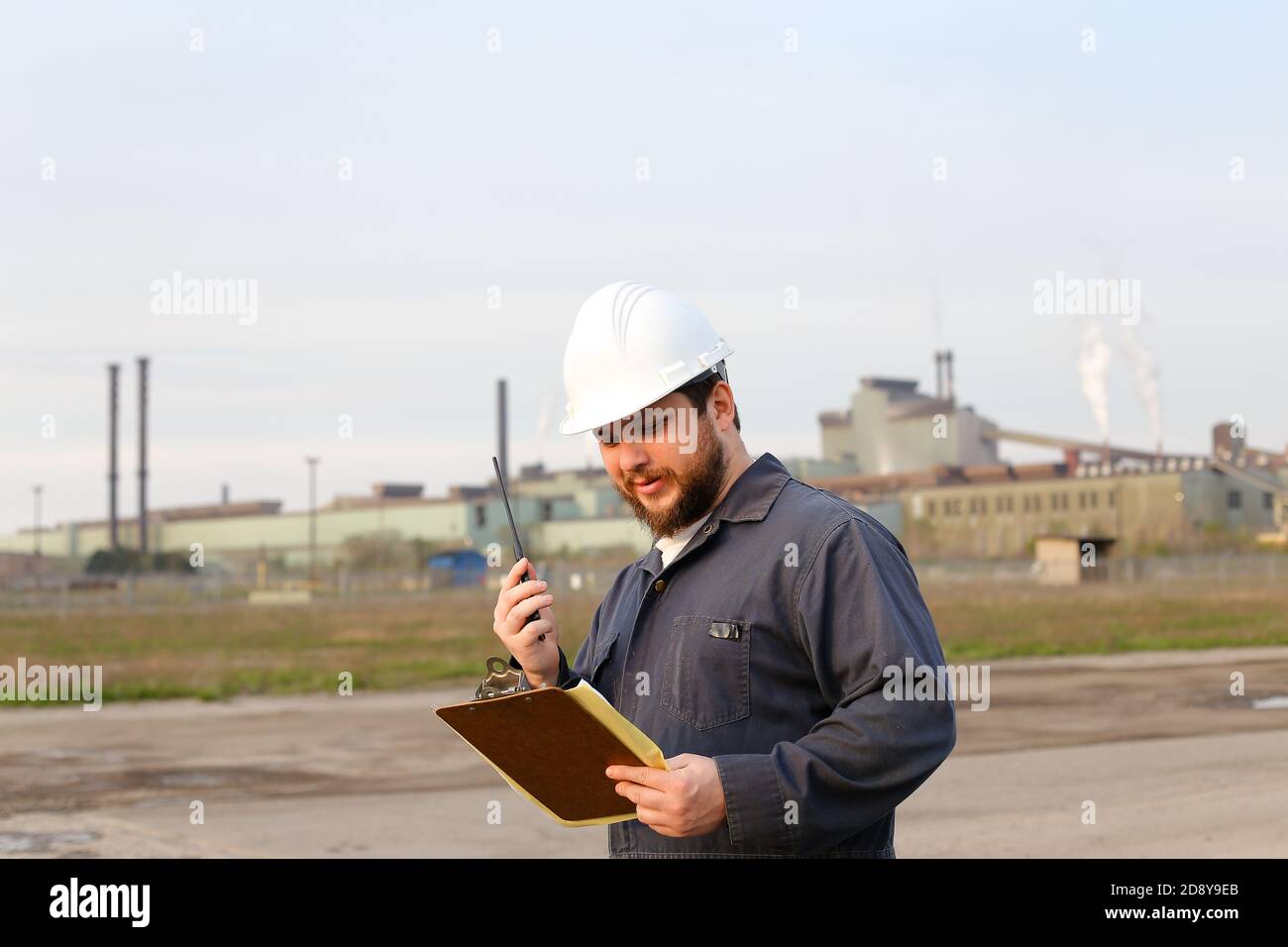 Foreman engineer standing on construction site and holding papers. Stock Photo
