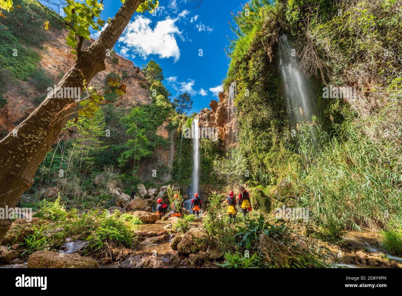 Unrecognizable people enjoy waterfall descent using ropes Stock Photo