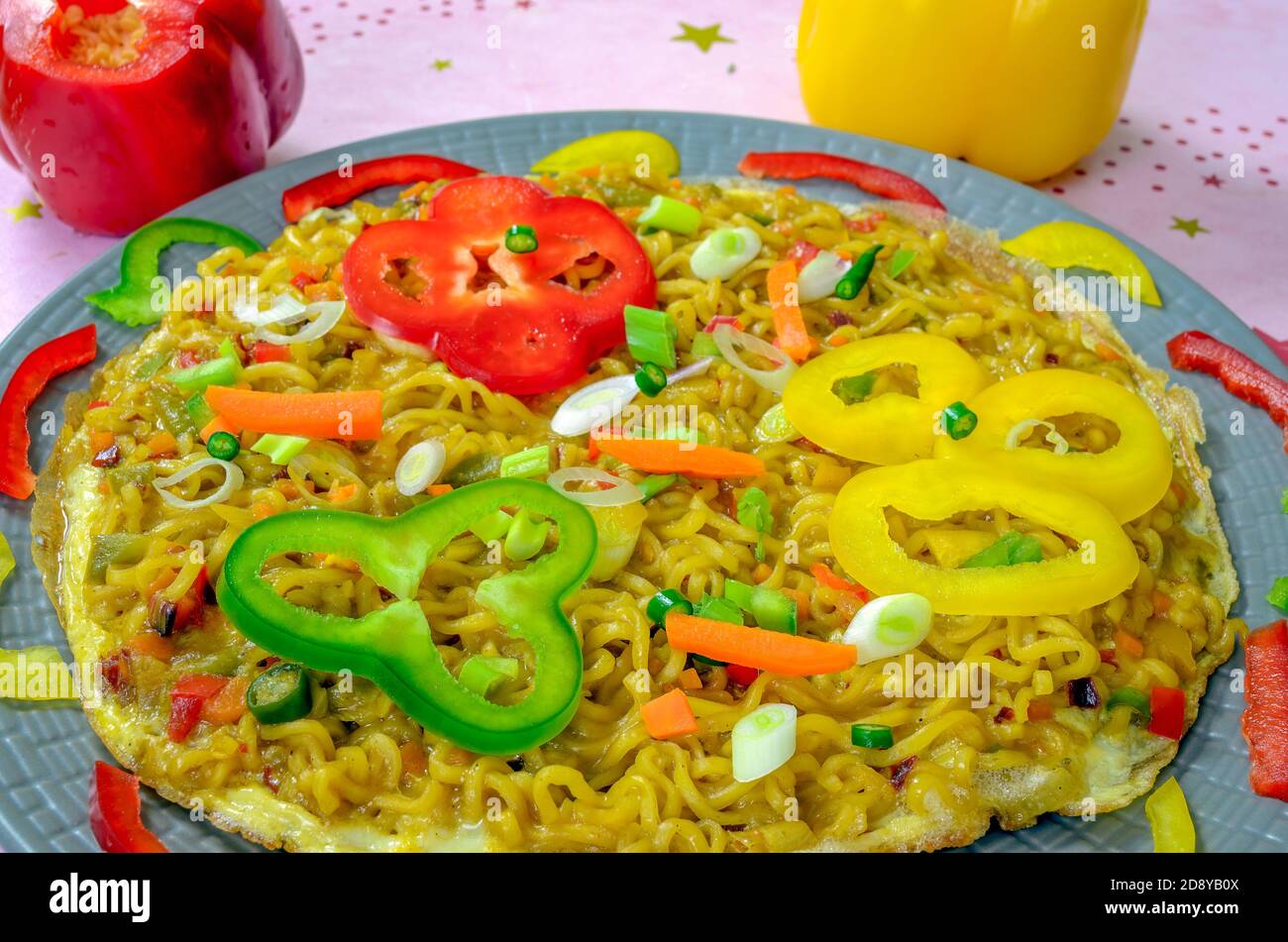Colorful slices of capsicums garnished over a delicious & ready-to-eat Noodles Omelette Stock Photo