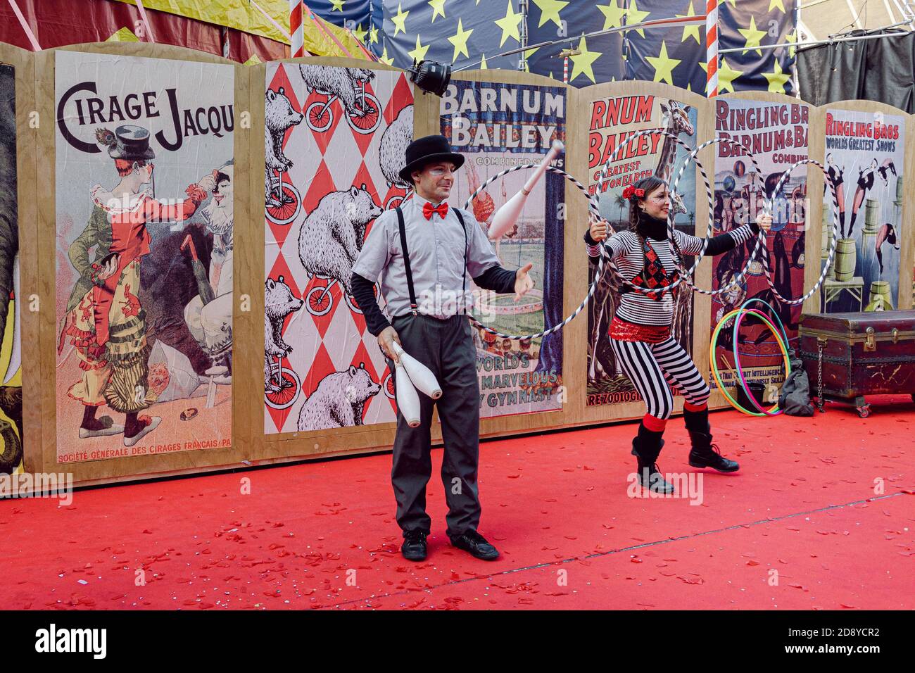 Circus performers in Venice during the Carnival playing with hula hoops and skittles on a red carpet Stock Photo