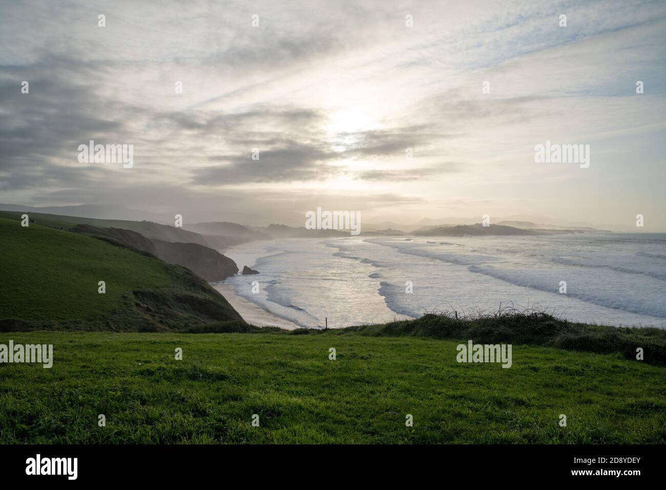 Tall green grassy cliffs drop down to the ocean coast in northern Spain Stock Photo