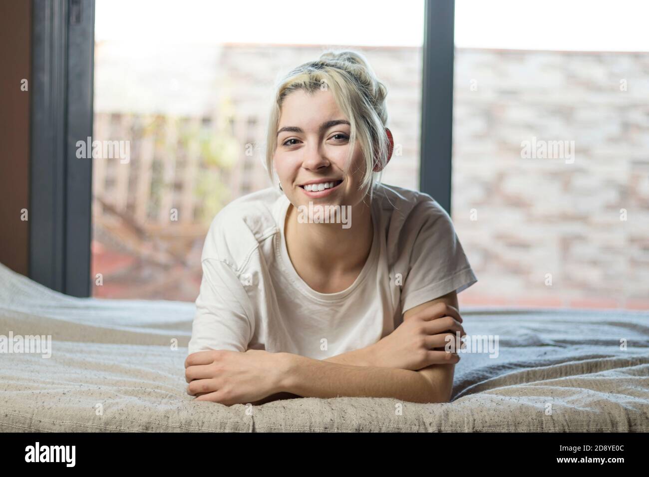smiling girl lying in bed and looking at camera at morning Stock Photo ...
