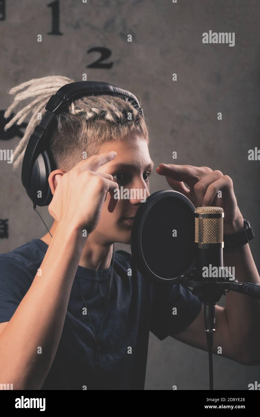 Young singer with dreadlocks of Caucasian appearance records a single in the studio. Vertical