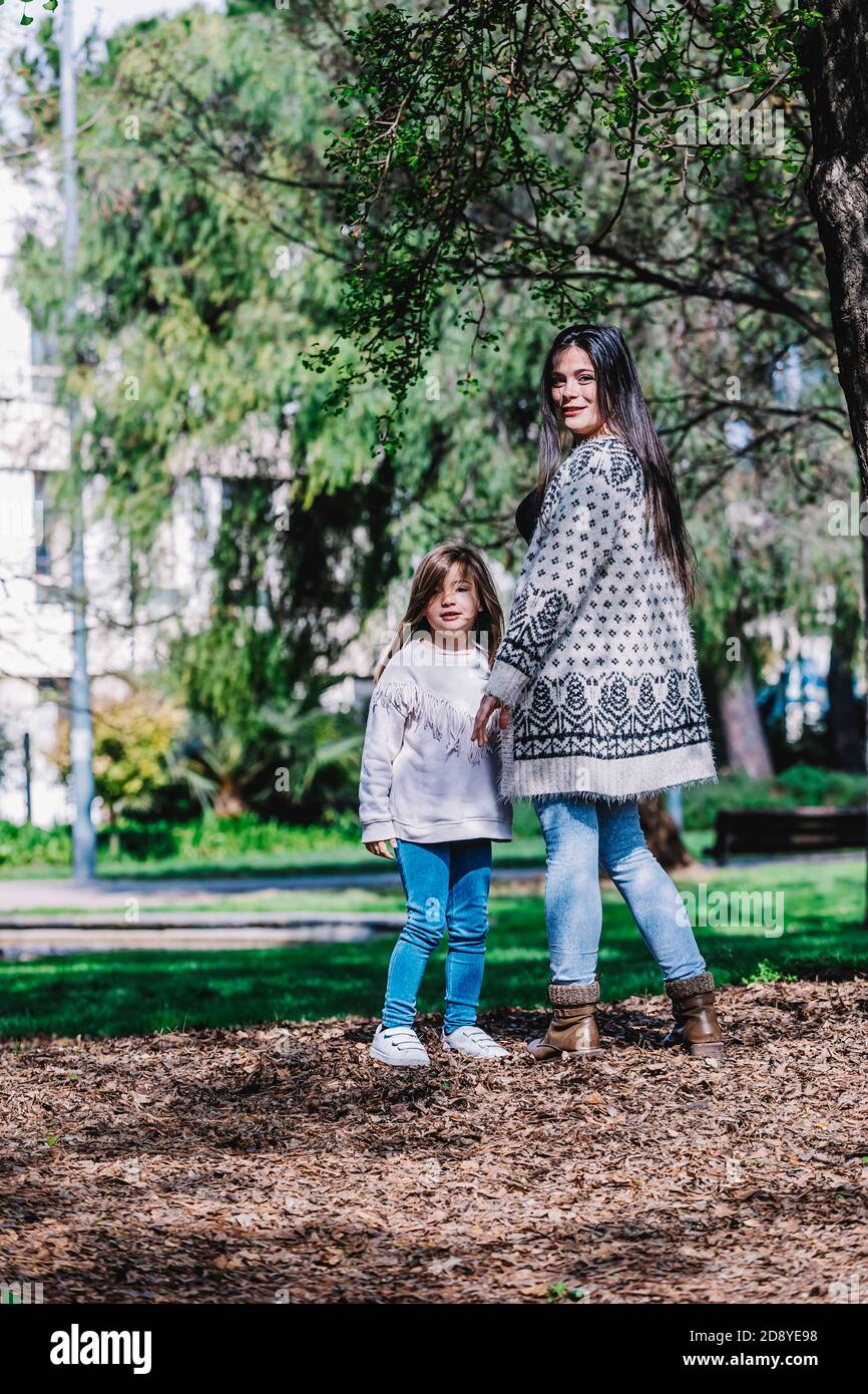 Rear view of a mother with her baby. Mom and daughter in an autumn park ...