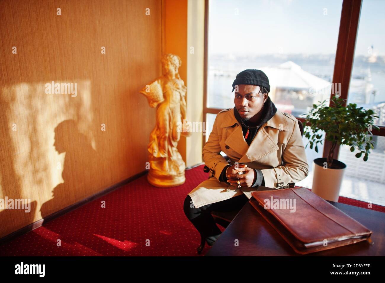Handsome african american man posing inside room with sunlight shadows ...