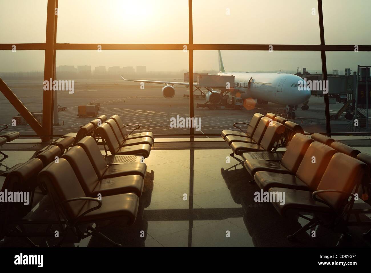 Aircraft flight preparation - fueling, catering, baggage services before airplane takeoff. Waiting area with chairs in international airport terminal Stock Photo