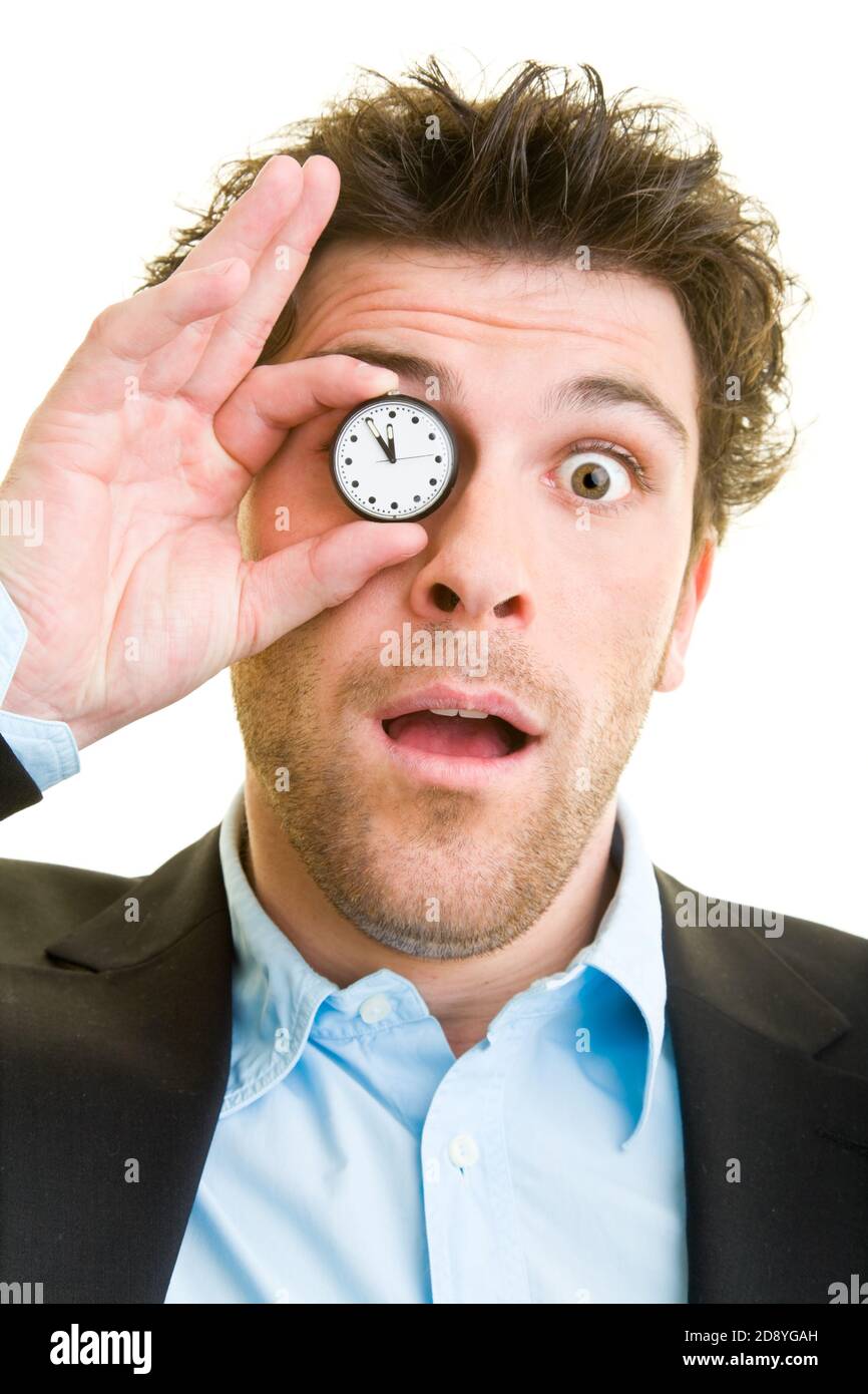 Young man in a suit holds a pocket watch in front of his eye Stock