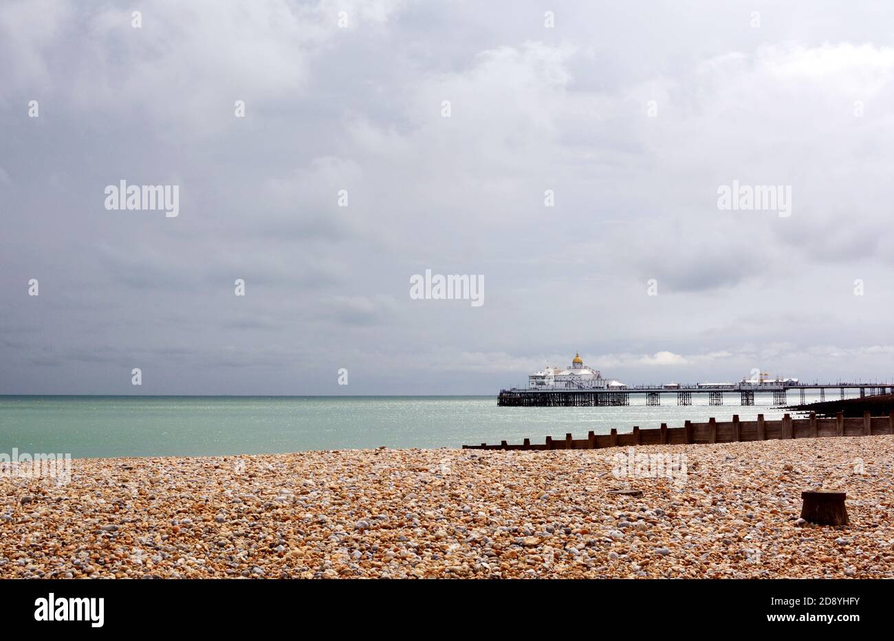View across shingle beach to Eastbourne pier on the English coast, with stormy summer skies Stock Photo