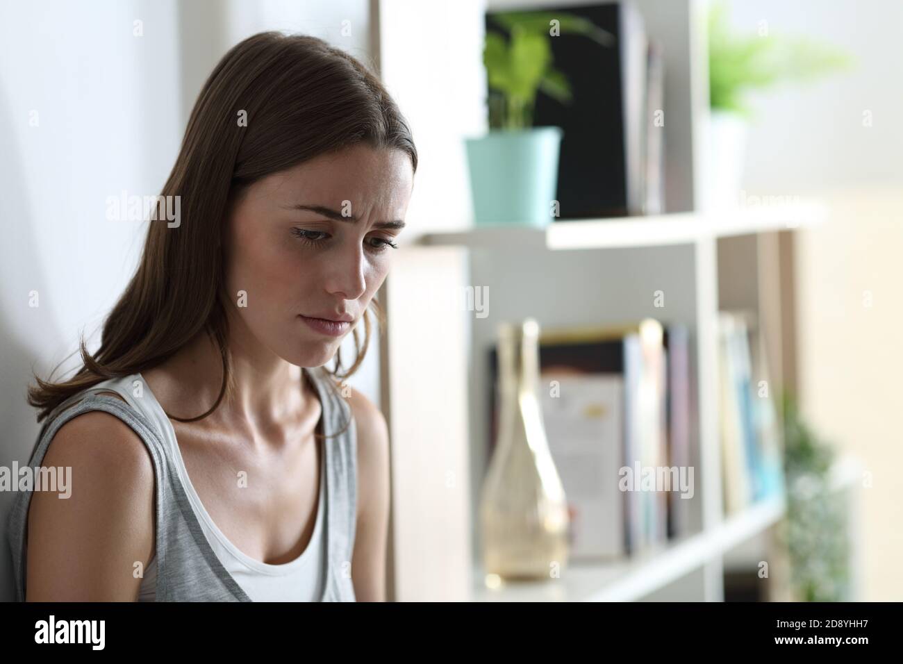 Sad teen complaining looking down leaning in a wall at home Stock Photo