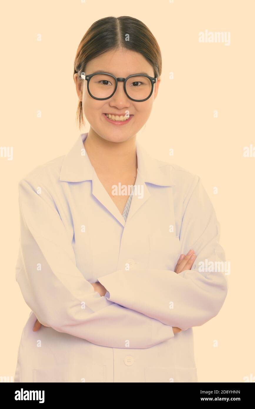 Studio shot of young happy Asian woman doctor smiling with arms crossed ...