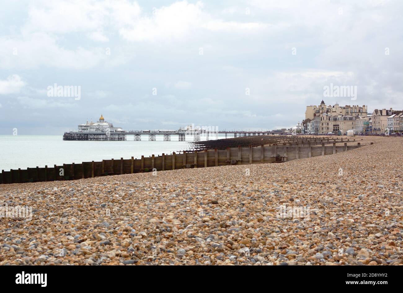 Eastbourne pebble beach in East Sussex with the famous Eastbourne pleasure pier above the sea in the distance Stock Photo