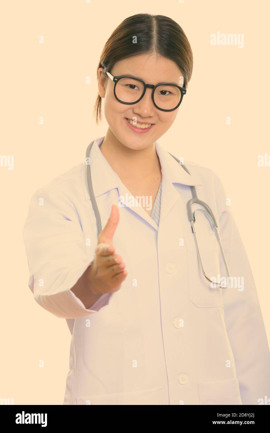 Studio shot of young happy Asian woman doctor smiling while giving ...