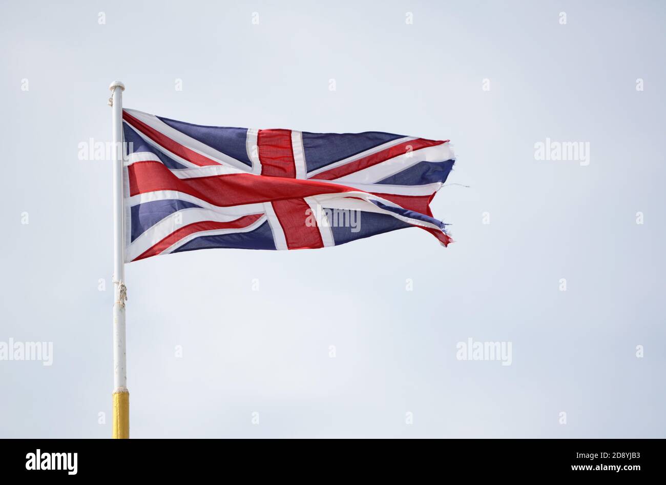 Union Jack flag representing Scotland, Wales, Northern Ireland and England, flies against a light blue sky Stock Photo