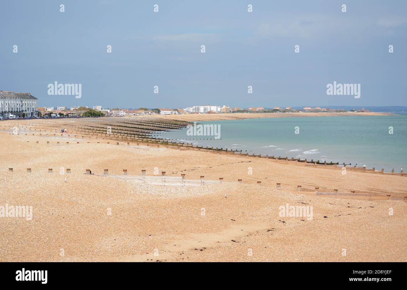 Eastbourne shingle beach in East Sussex, almost deserted on a sunny summer day. Hotels, houses and businesses line the edge of the beach. Stock Photo