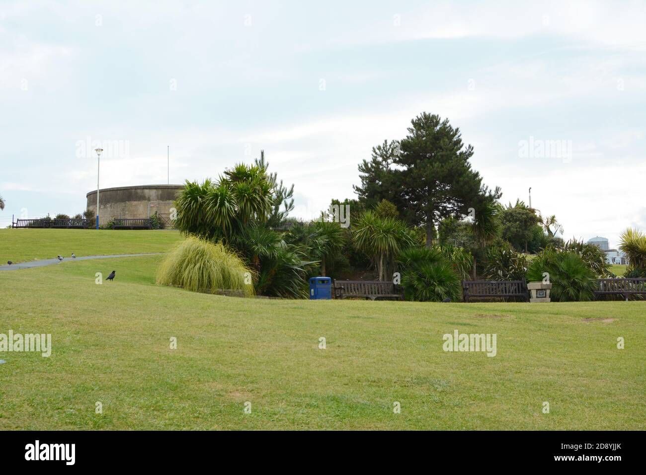 Grass slope with seating, shrubbery and trees in front of the historic Redoubt fortress on Royal Parade in Eastbourne Stock Photo