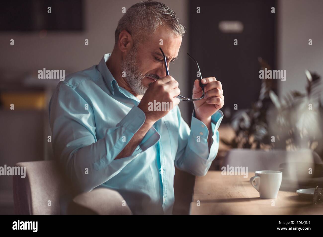 Middle aged bearded man putting on his eyeglasses Stock Photo