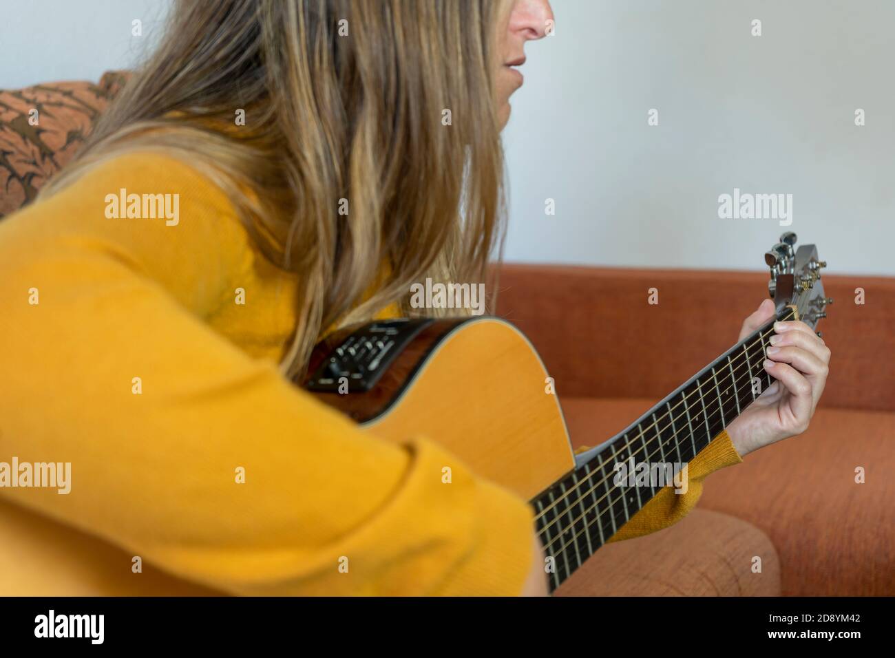 Young girl playing western acoustic guitar at home.Lifestyle music and entertainment concept. Stock Photo