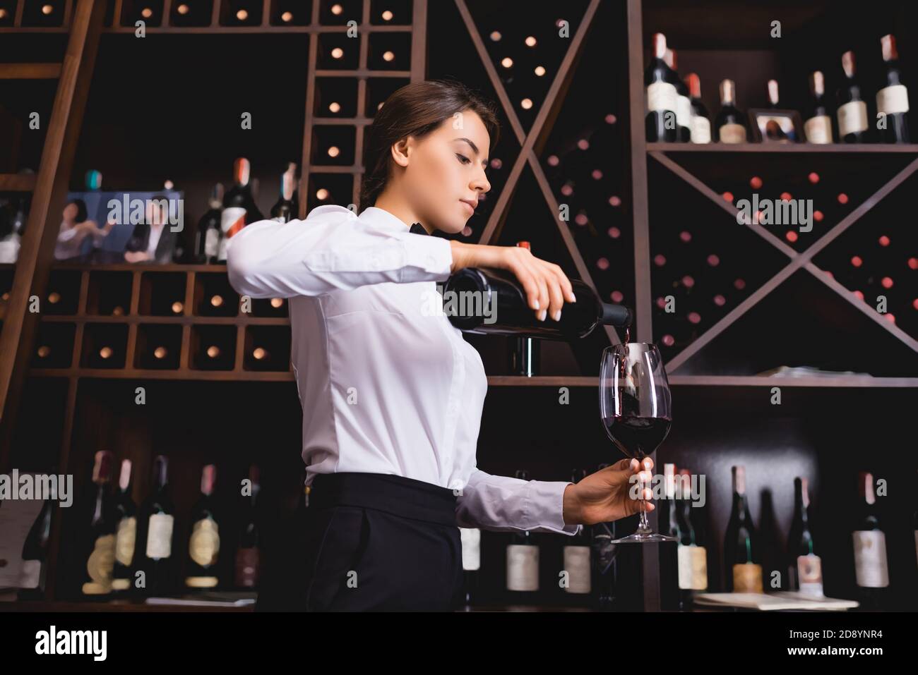 Brunette sommelier pouring wine from bottle in restaurant Stock Photo