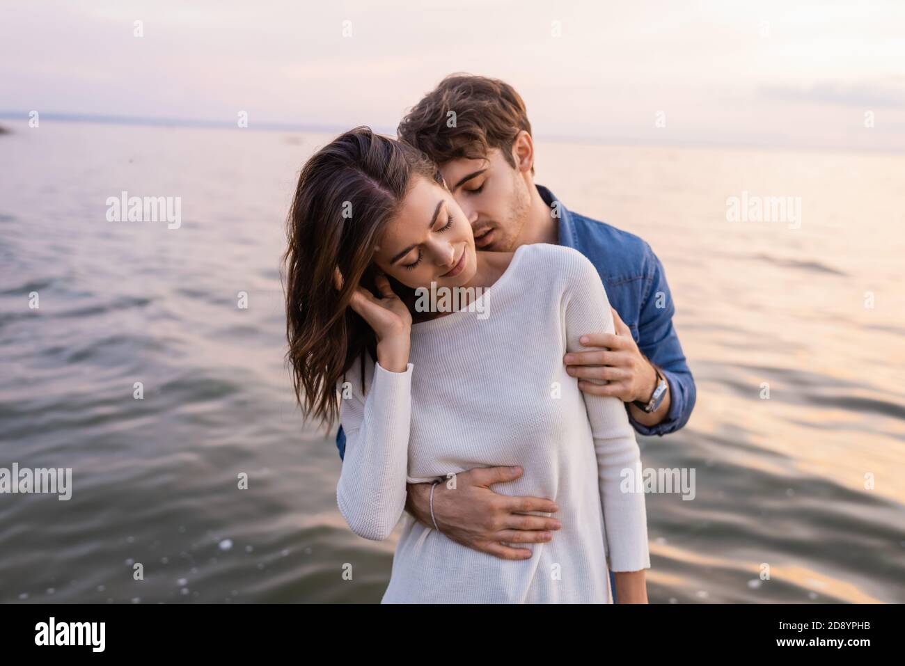 Man Kissing Neck And Hugging Girlfriend Near Sea At Evening 2D8YPHB 