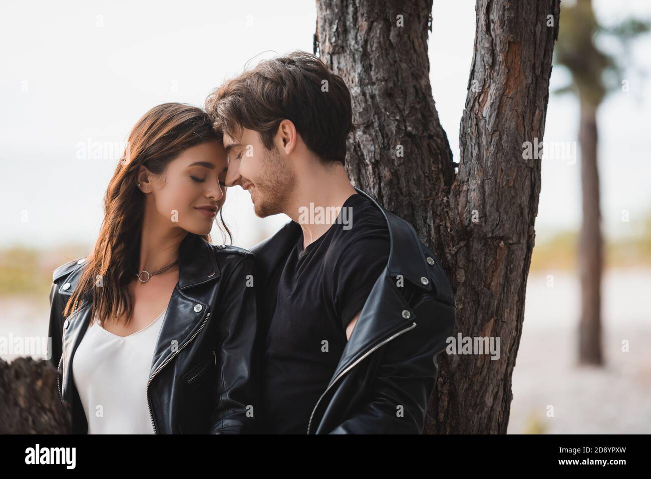 Selective focus of brunette woman in leather jacket standing near ...