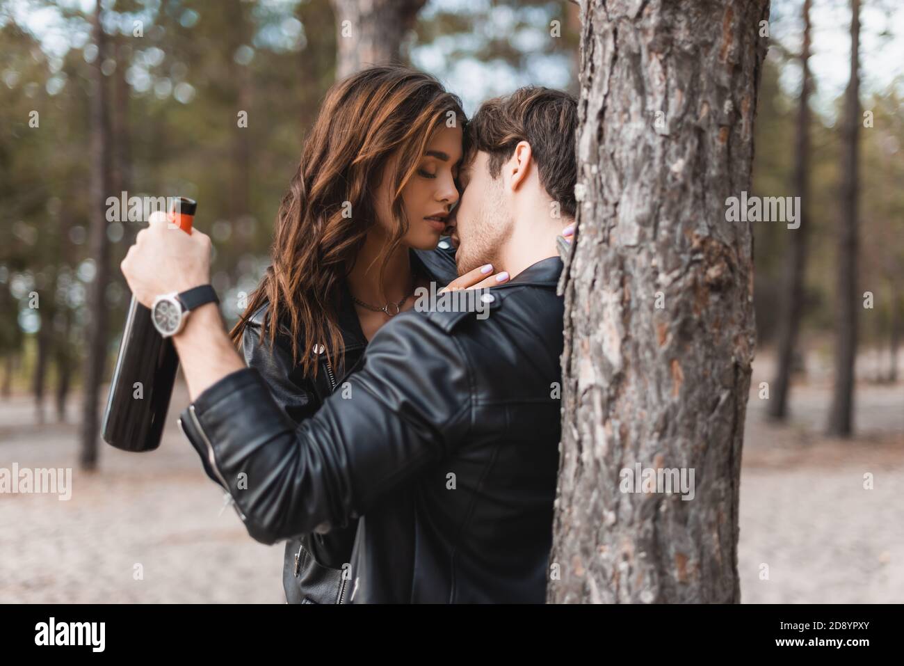 Selective focus of man in leather jacket kissing girlfriend and holding ...