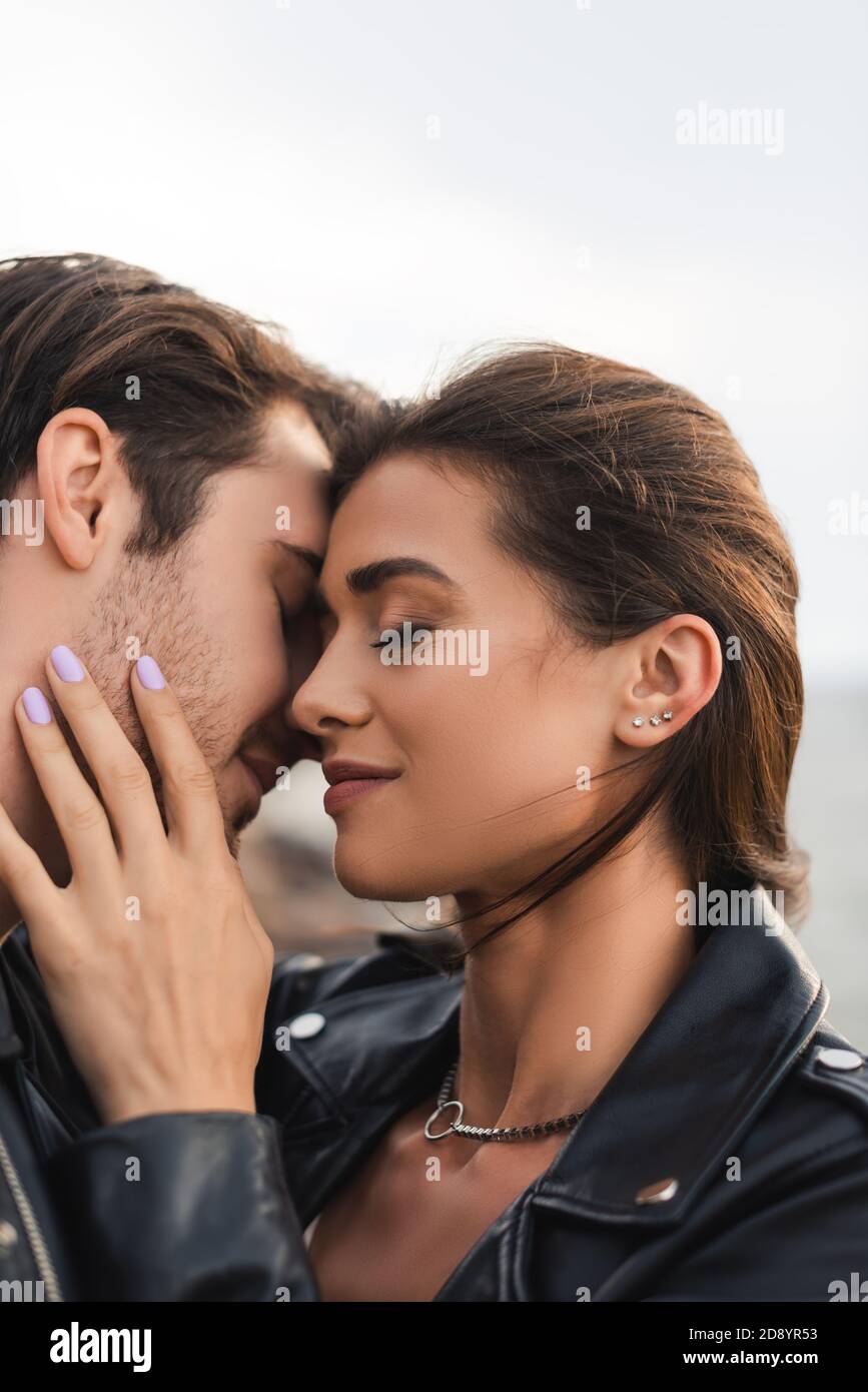 Young woman in leather jacket touching boyfriend with closed eyes ...