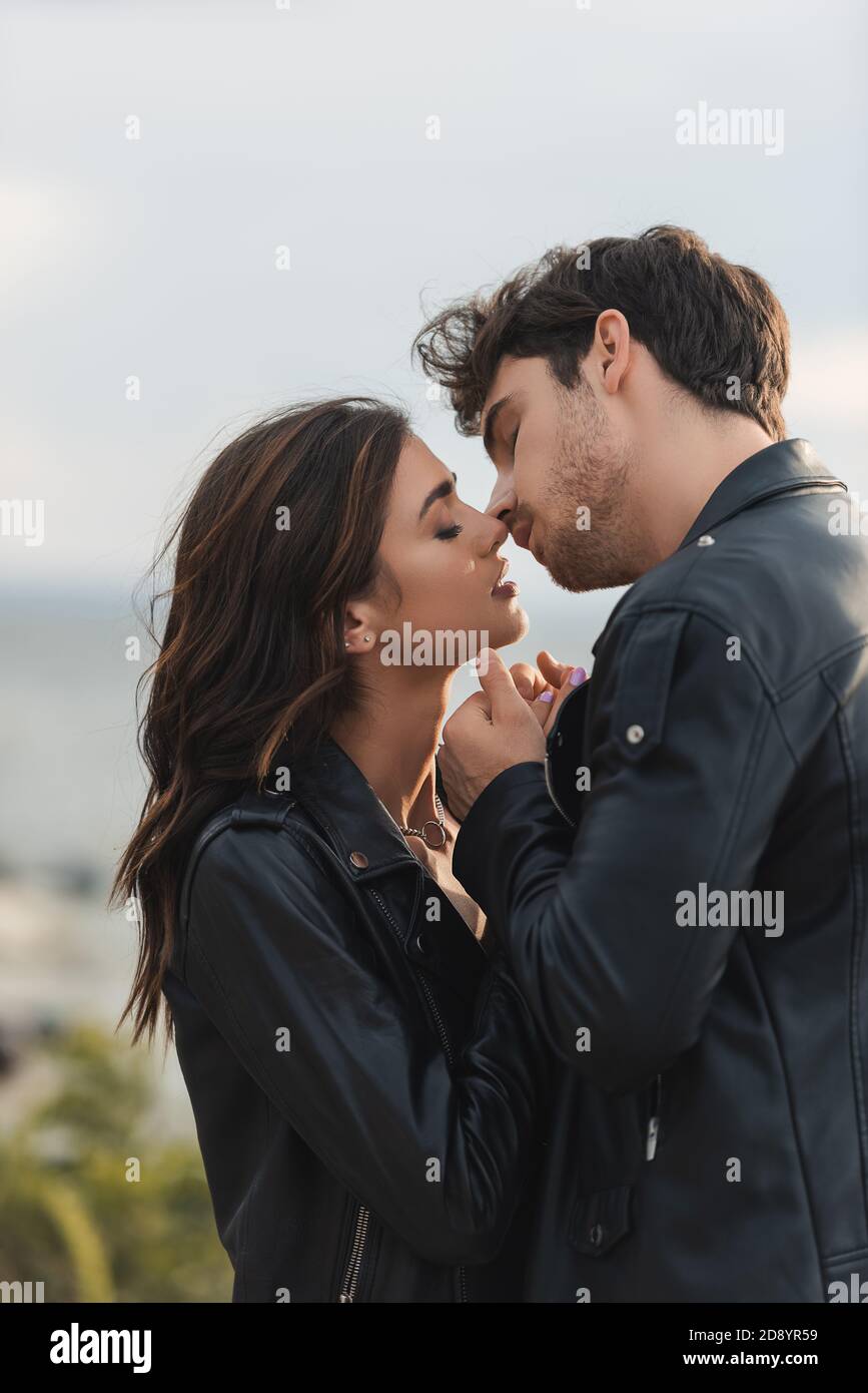 Young couple in leather jackets kissing with closed eyes outdoors Stock ...