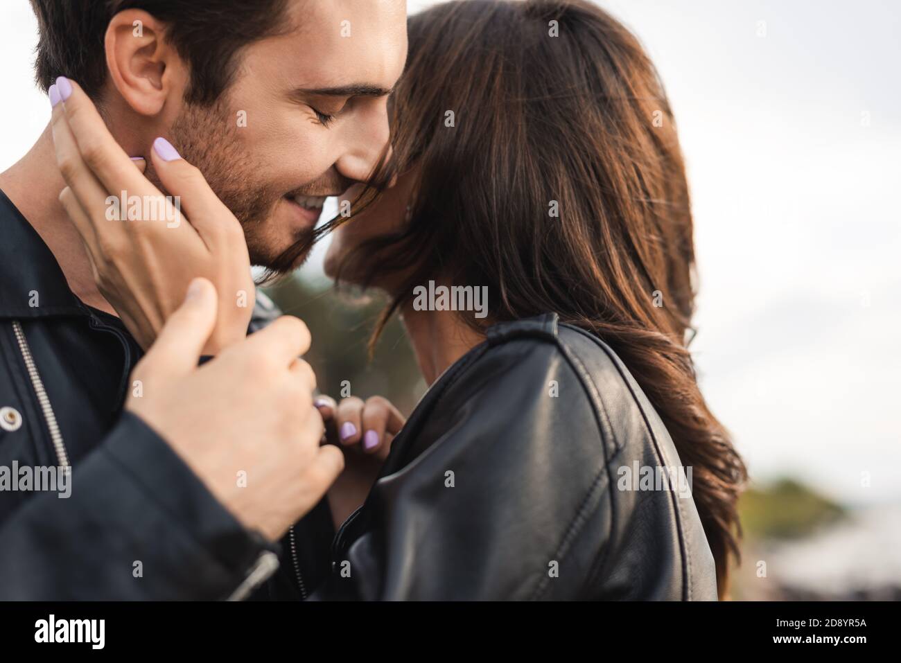 Selective focus of woman in leather jacket touching boyfriend outdoors ...