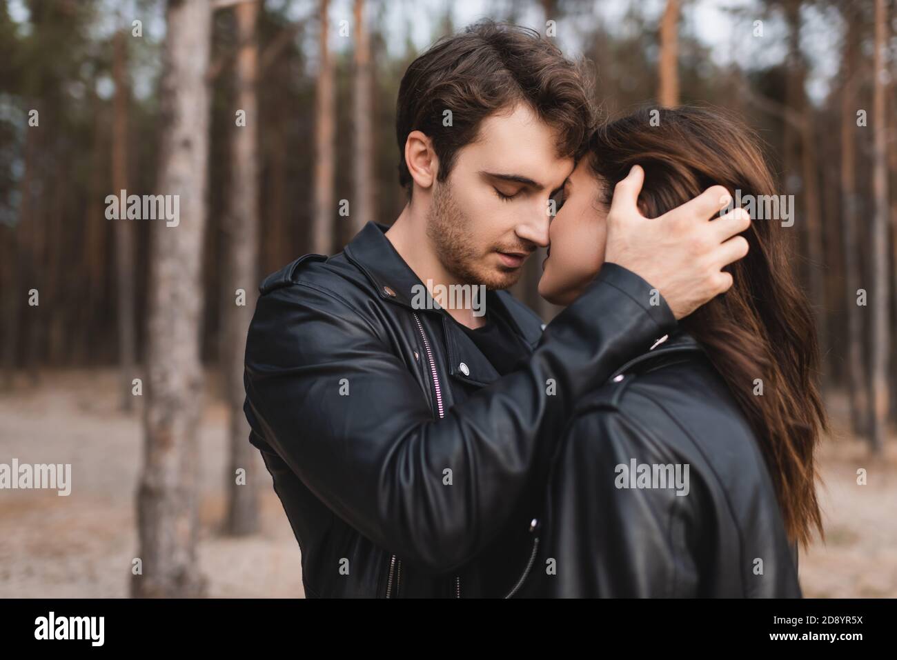 Man in leather jacket kissing and touching girlfriend in forest Stock ...