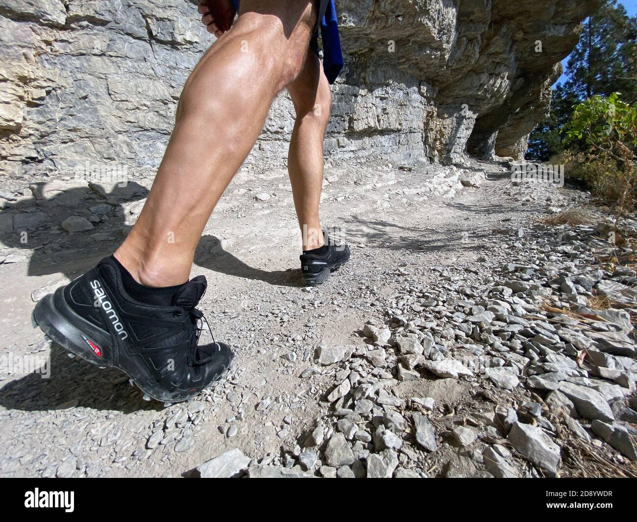 Sochi, Russia - October 6, 2020: legs man in running shoes Salomon Speedcross 4 gtx hiking on mountain trail Stock Photo