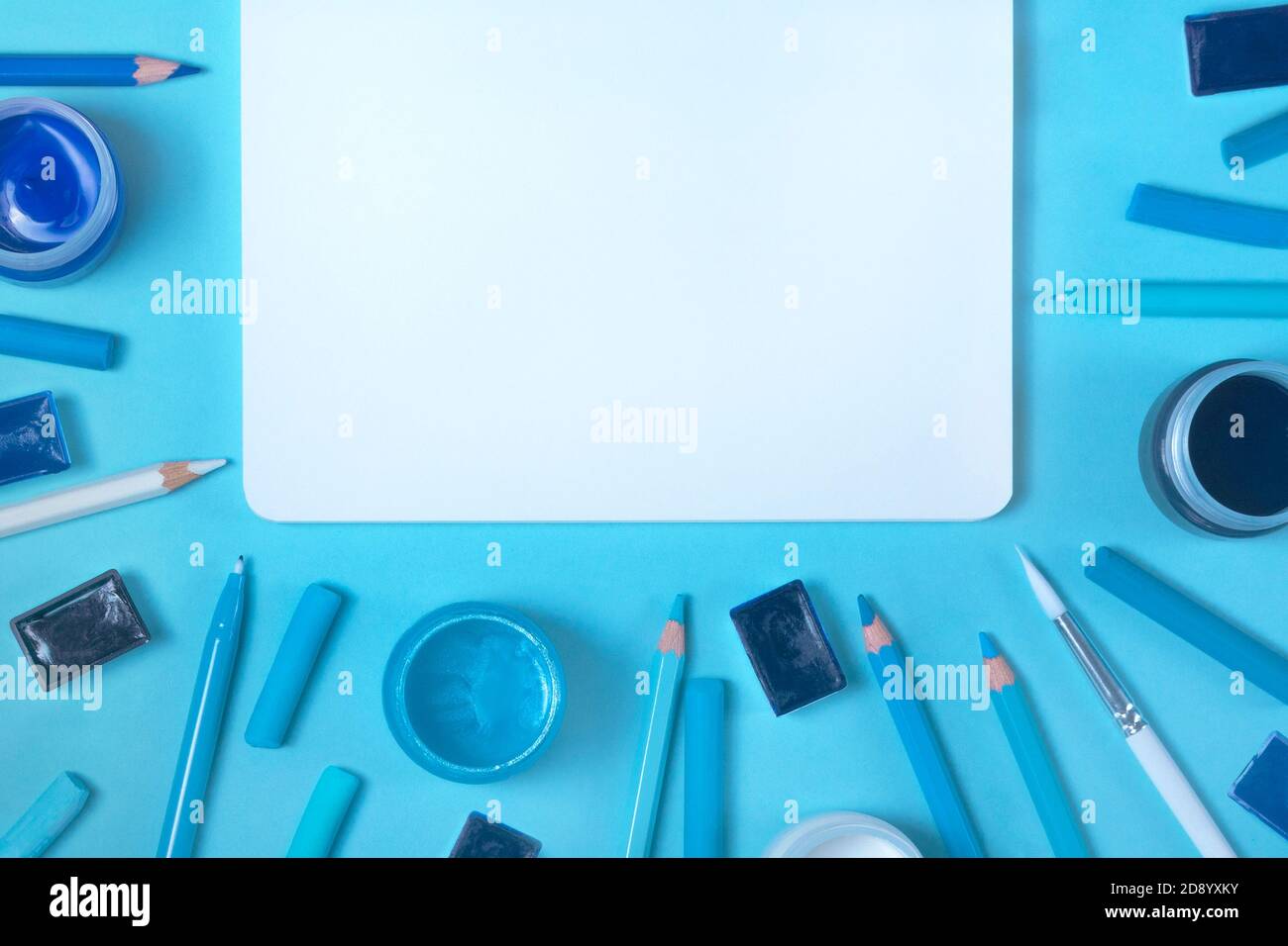 Painter working desk with watercolor, gouache, acrylic, palette, pencils, pastel, brush, sketchbook mockups on blue background. Flat lay top view Stock Photo