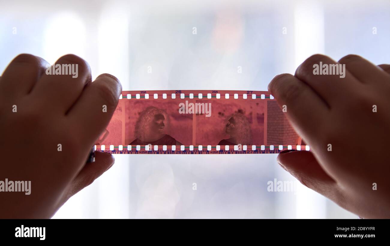 A woman holds a negative from an old film camera, closeup Stock Photo