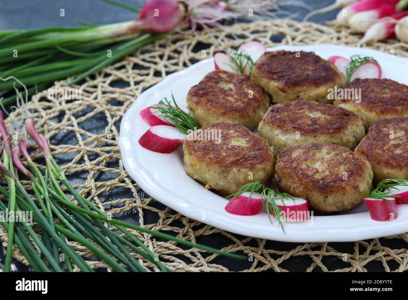 Fish patties on a white plate against a dark background Stock Photo